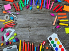  school supplies scattered on grey wooden table